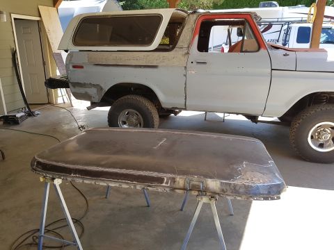 1978 Ford Bronco - A partially disassembled Ford Bronco is shown with its roof removed and resting on sawhorses in the foreground. The vehicle appears to be u…