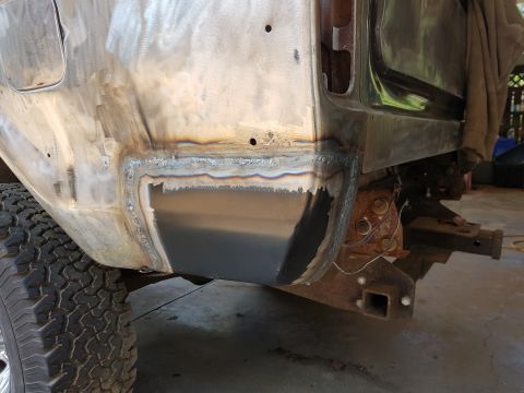 1978 Ford Bronco - A close-up view of the rear quarter panel of a vehicle undergoing repair, showing fresh welds and a newly installed metal patch on the lowe…