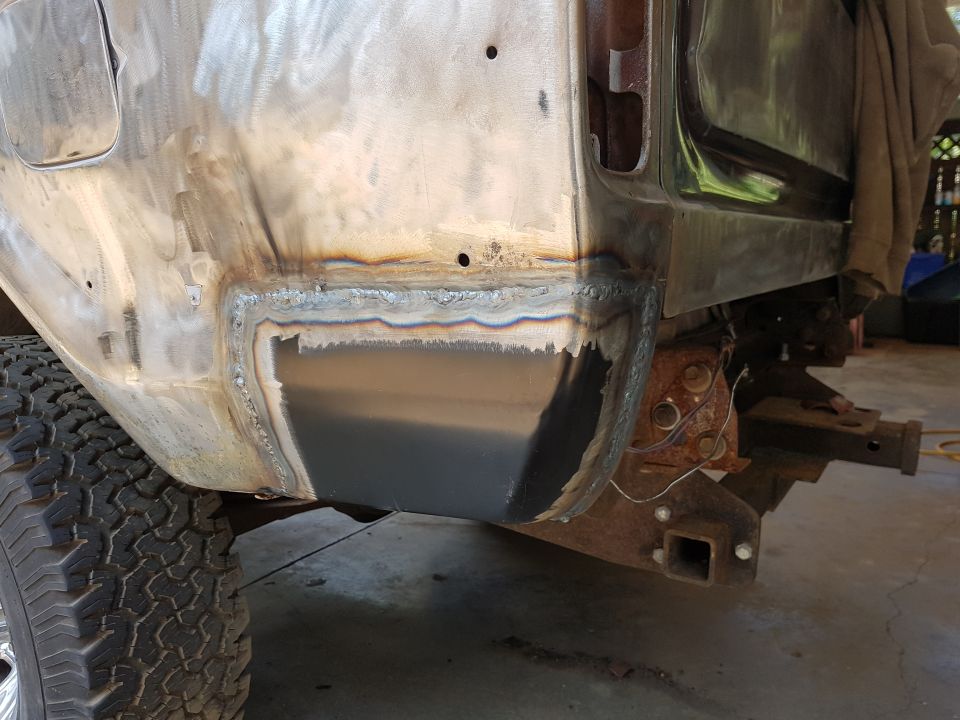 Vehicle rear quarter panel with fresh welds and a new metal patch, tire, and trailer hitch.