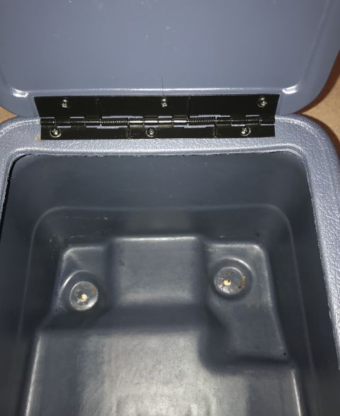 1995 Ford Bronco - An open grey plastic storage bin with a black metal hinge attached to the lid and the bin's rim. Two circular indentations with visible scr…
