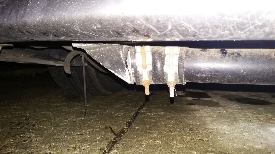 Underside of a vehicle showing exhaust pipe and hangers.