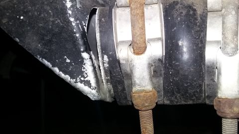 Close-up of a black rubber boot with a metal clamp and rusty bolt.