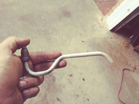 1996 Ford Bronco - A hand holds a bent metal tube with a threaded fitting on one end. The tube appears to be a part of a vehicle's fluid or brake system.