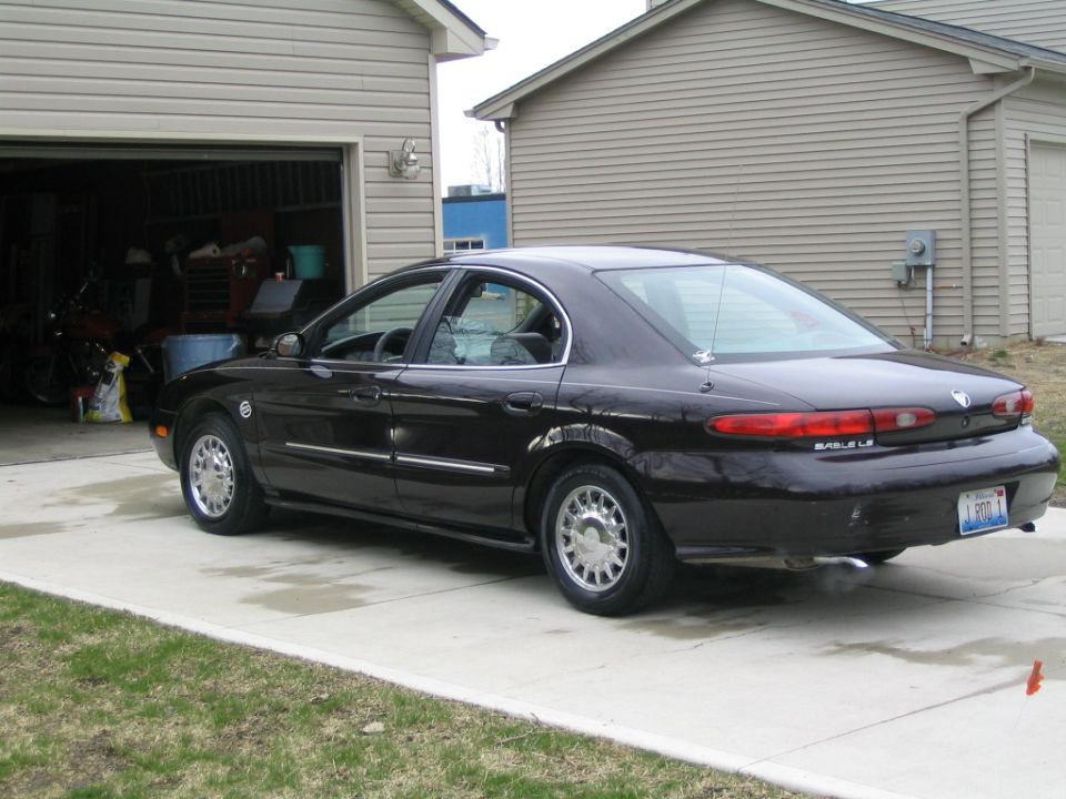 Dark 1996 Mercury Sable sedan parked on a concrete driveway in front of a garage