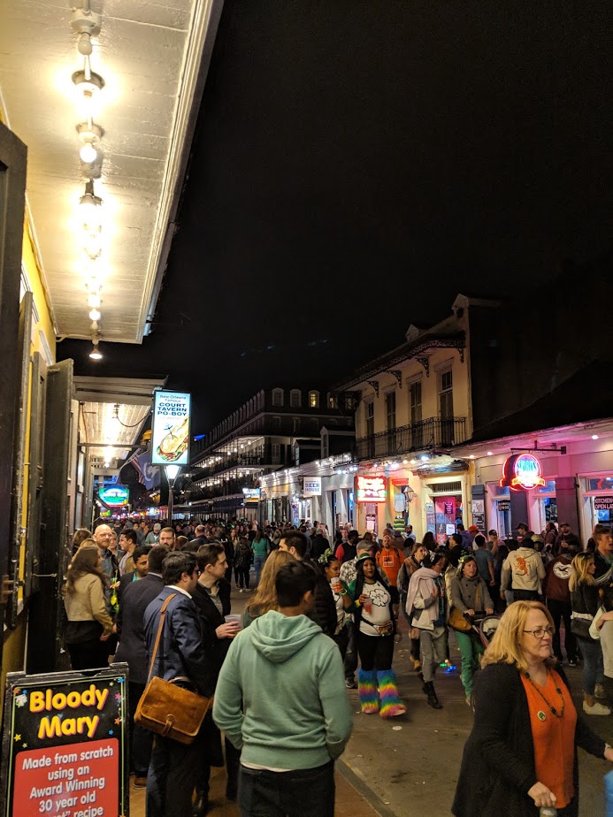 Crowded street at night with people and illuminated signs.
