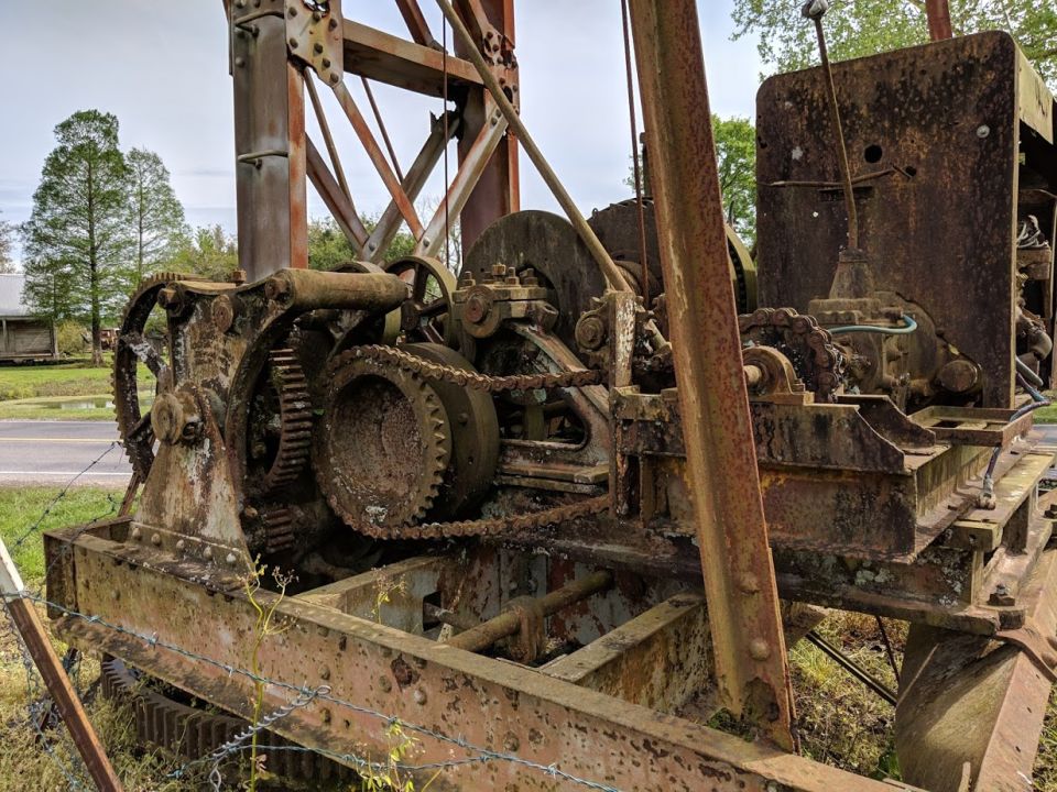 Rusted industrial machinery with gears and chains, outdoors.