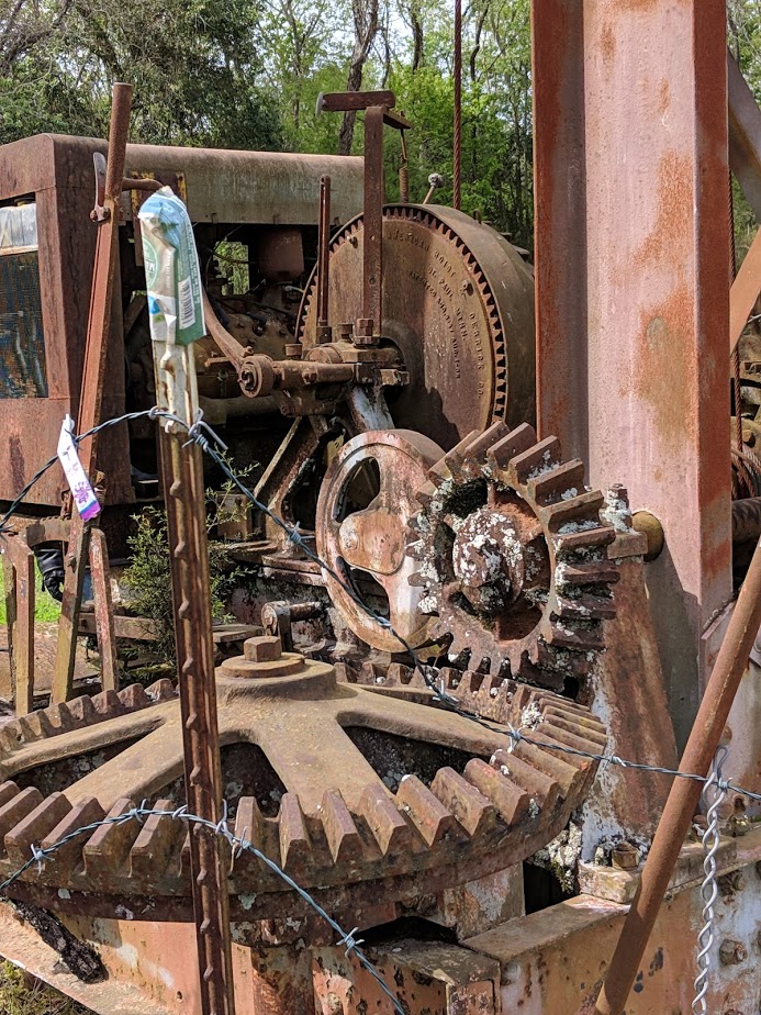 Close-up of rusty industrial machinery with large gears and weathered metal.