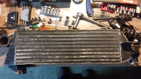 Used intercooler with tools on a workbench.