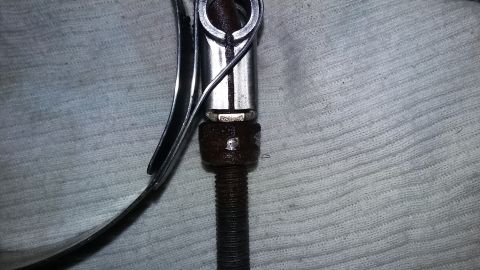 Close-up of a metal clamp with threaded screw and nut on textured surface