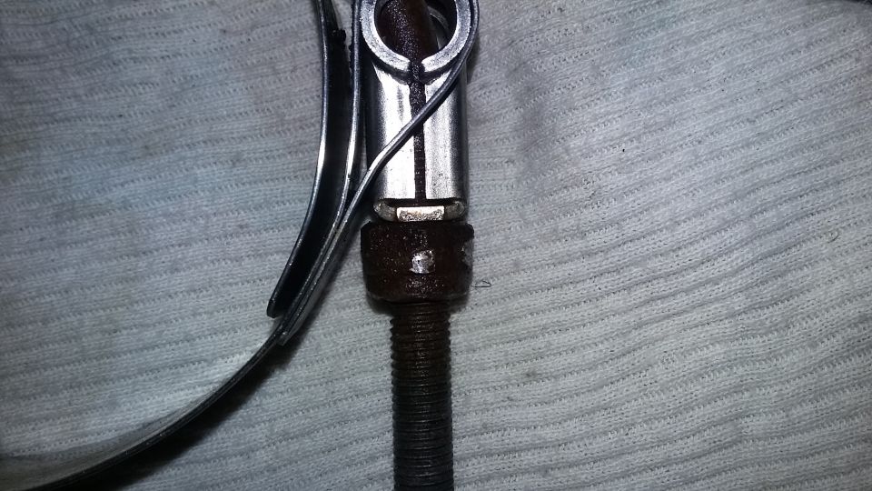Close-up of a metal clamp with threaded screw and nut on textured surface