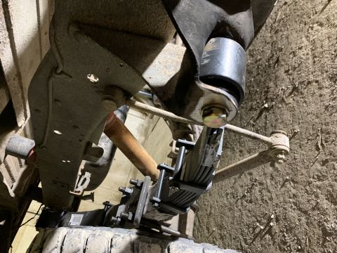 1979 Ford Bronco - Underside view of a vehicle's suspension system, showing leaf springs, a sway bar link, and a large rubber bushing attached to a metal brac…