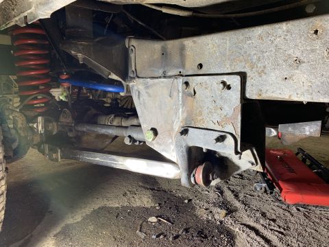 1979 Ford Bronco - A close-up view of the undercarriage of a vehicle, showing suspension components including a red coil spring, a blue sway bar, and a differ…