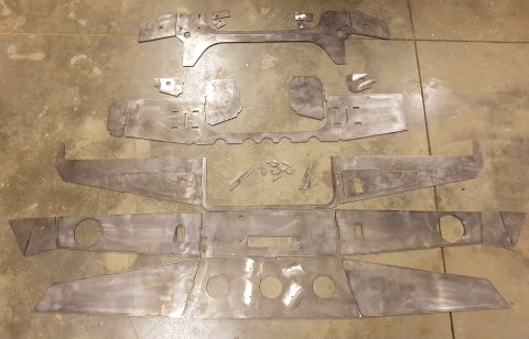 1978 Ford Bronco - A collection of flat, unpainted metal parts, likely for a vehicle modification, are laid out on a concrete floor. The parts vary in size an…