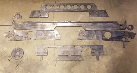 1978 Ford Bronco - A collection of unpainted metal fabrication parts, likely for a vehicle build, are laid out on a concrete floor. The parts include various…