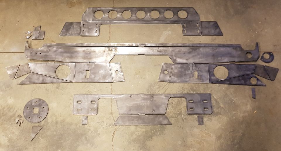 Unpainted metal fabrication parts for a vehicle build on a concrete floor.
