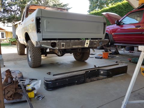1978 Ford Bronco - The rear of a gray, unfinished 1978 Ford Bronco is shown with a custom metal bumper being fabricated. A red SUV is parked behind it with it…