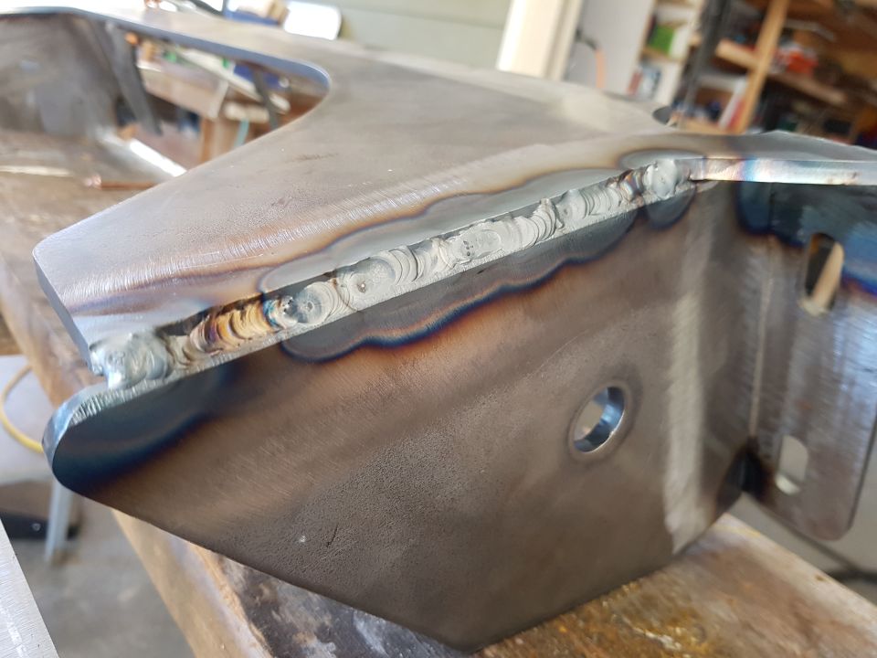 Welded metal automotive part with heat discoloration and holes.