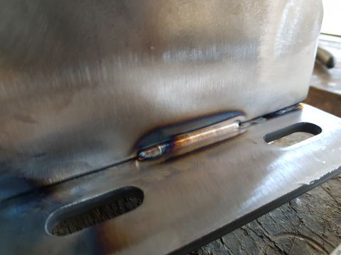 1978 Ford Bronco - A close-up shot shows a metal bracket that has been welded. The weld shows discoloration from heat, with iridescent blues and yellows.