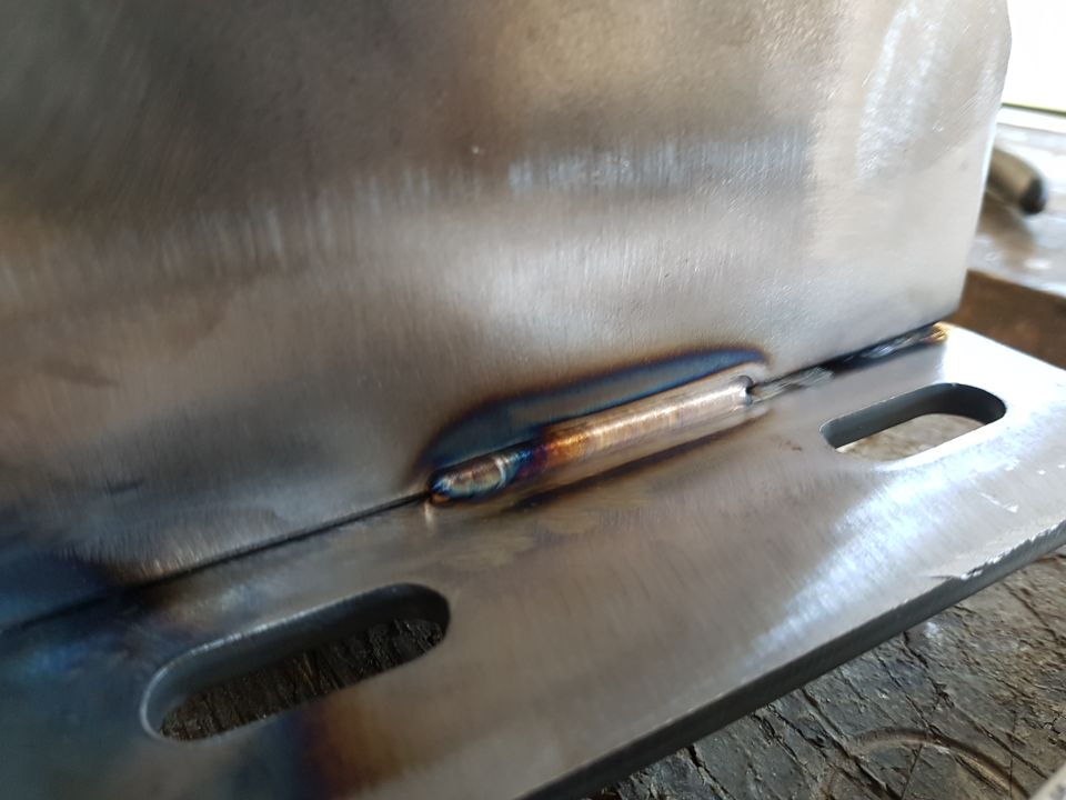 Close-up of a metal bracket with a heat-discolored weld.