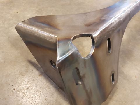 1978 Ford Bronco - A custom metal bracket with a raw, unfinished appearance sits on a concrete floor.