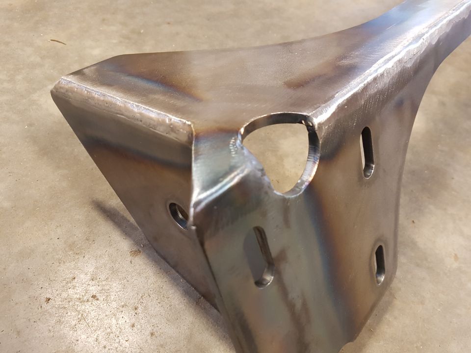 Close-up of a welded metal bracket with cutouts and holes