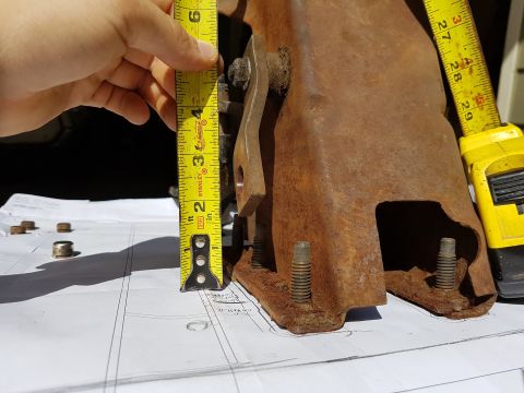 1978 Ford Bronco - A rusty metal bracket is measured with a tape measure.