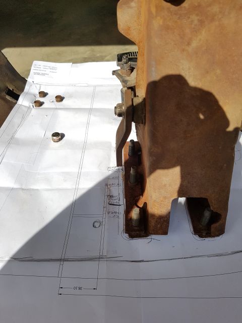 1978 Ford Bronco - A rusty metal bracket is positioned over a set of blueprints, indicating a measurement or alignment process.