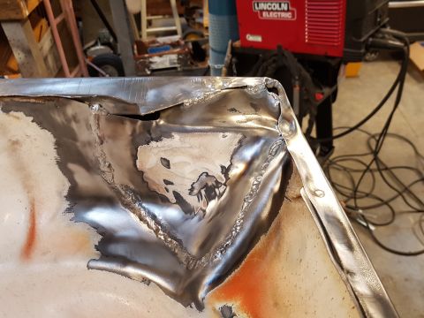 1978 Ford Bronco - Close-up of a heavily damaged metal panel undergoing welding repairs.