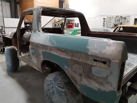 1978 Ford Bronco - Ford Bronco body in a workshop, showing primer and body filler during restoration work.