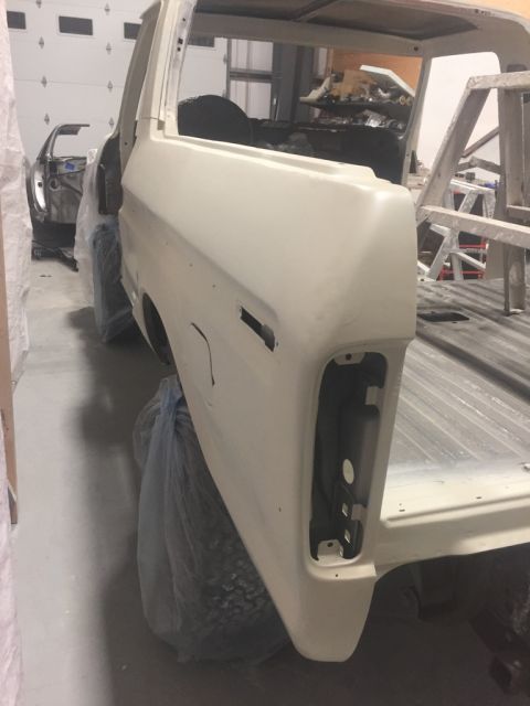 1978 Ford Bronco - Body of a 1978 Ford Bronco in primer, with another vehicle undergoing work in the background.