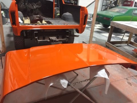 1978 Ford Bronco - Orange 1978 Ford Bronco rear section in a workshop, with its freshly painted hood in the foreground.