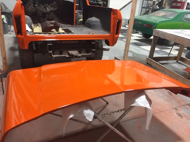 Orange 1978 Ford Bronco rear in workshop with hood in foreground