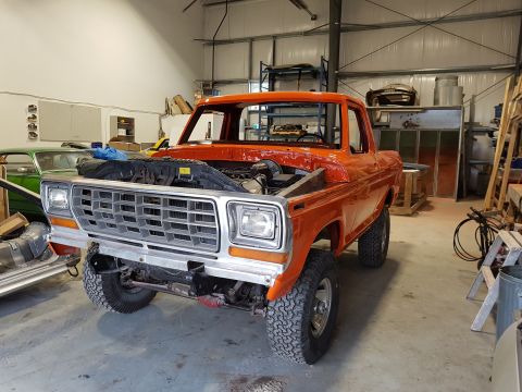 1978 Ford Bronco - This 1978 Ford Bronco is undergoing restoration in a garage, with its hood open revealing the engine bay.