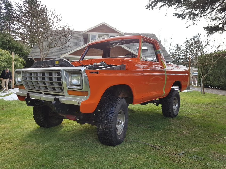 Orange 1978 Ford Bronco with hood open, parked on grass