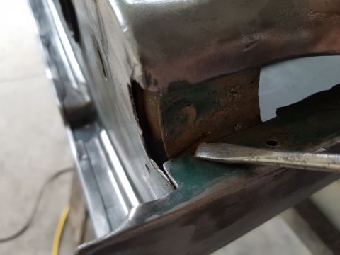 1978 Ford Bronco - Detail of corroded metalwork on a vehicle part, with a tool probing a gap.