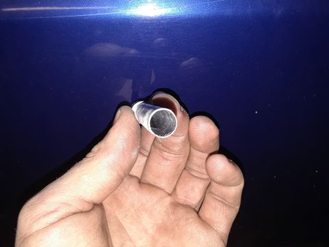 1985 Ford Bronco - A hand holds a metal tube, possibly a part for a vehicle repair.