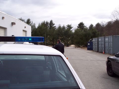2001 Ford Crown Victoria - Police car with light bar in foreground, a person on a motorcycle is visible in the background.