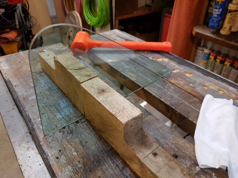 1978 Ford Bronco - A glass pane is positioned on a wooden jig, with an orange mallet nearby, suggesting preparation for cutting or fitting.