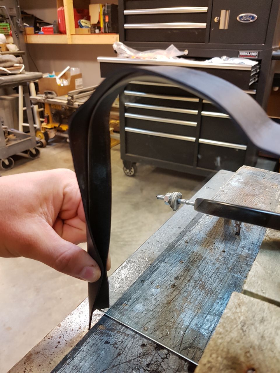 Hand holding black rubber seal over metal edge