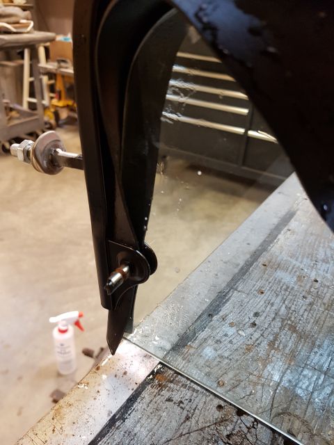 1978 Ford Bronco - Close-up of a metal bracket with a bolt and nut assembly on a workbench.