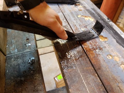 1978 Ford Bronco - A person is working on a black rubber trim piece on a wooden workbench.