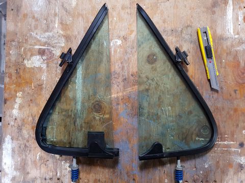 1978 Ford Bronco - Two vent windows are laid out on a wooden surface, ready for installation or repair.