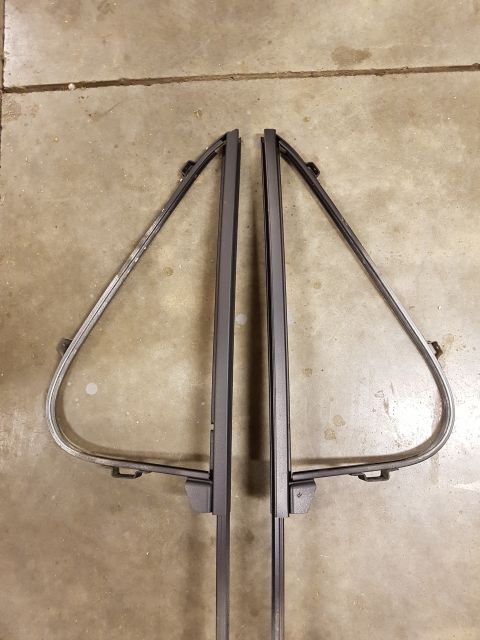 1978 Ford Bronco - Two vent window frames, likely for a classic vehicle, are laid out on a concrete surface.