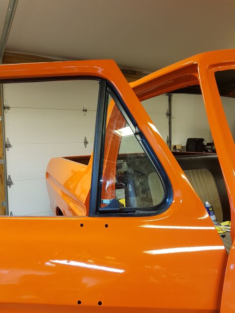 1978 Ford Bronco - The side profile of an orange 1978 Ford Bronco is visible, showing its body undergoing restoration work.
