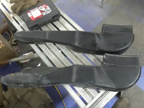 1996 Ford F-350 - Two black plastic air intake ducts are shown on a workbench with tools nearby.
