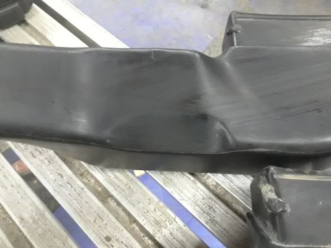 1996 Ford F-350 - Close-up of a dented black plastic engine cover, likely from a vehicle's engine bay.