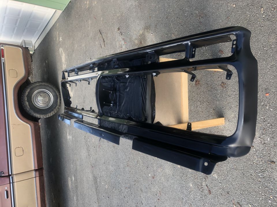 1978 Ford Bronco grille assembly with chrome accents and black plastic trim, resting on wooden blocks