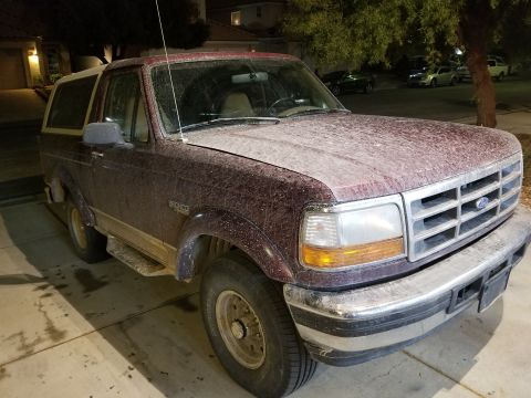 1993 Ford Bronco - This dusty maroon Ford Bronco is parked in a residential driveway.