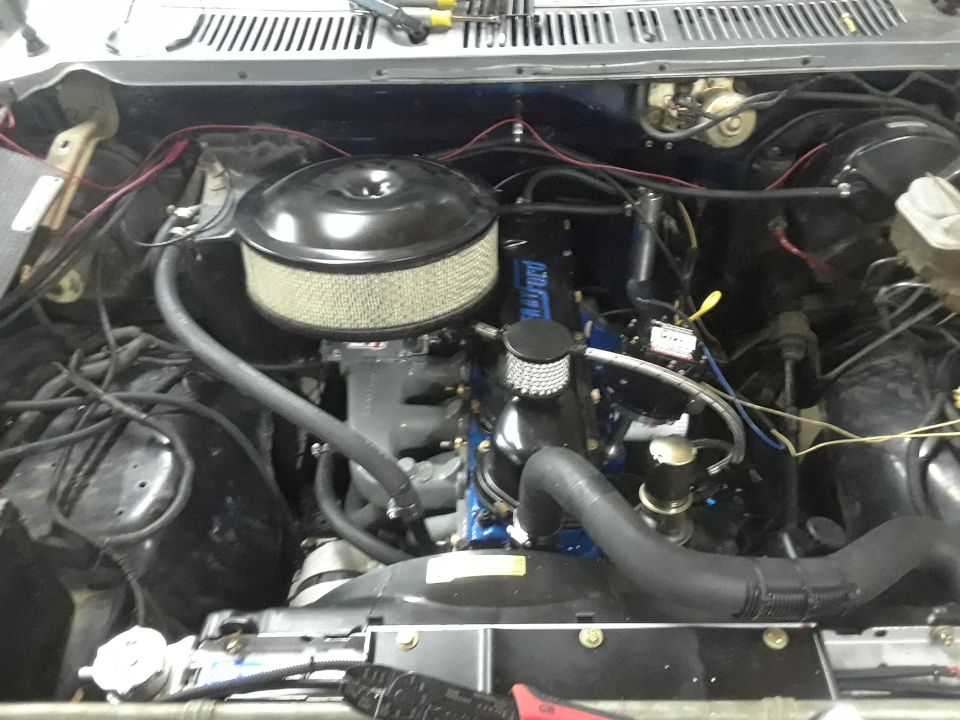engine bay with blue engine block, air filter, and hoses