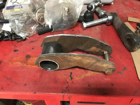 1984 Ford Bronco - Custom suspension components and assorted hardware are laid out on a red workbench.